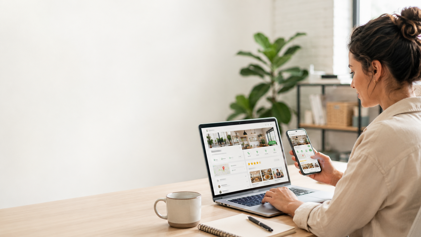 Small business owner reviewing a Google Business Profile on a laptop and phone in a bright modern office.